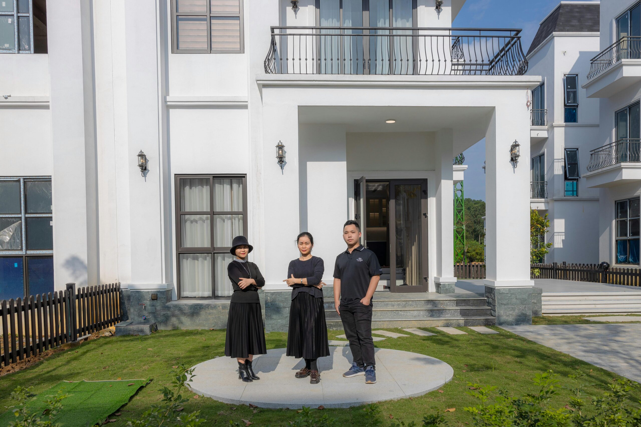Family standing confidently outside a modern house, showcasing real estate and lifestyle.